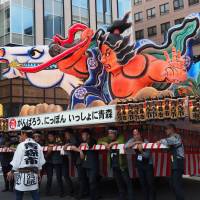 Men take a break before pushing a large Aomori Nebuta float down Shintora Street. While there are other nebuta festivals in Japan, Aomori\'s large festival, held annually in August, is the biggest. | MARK THOMPSON