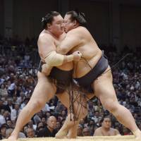 Kisenosato (right) grapples with Hakuho at the Kyushu Grand Sumo Tournament on Tuesday. Kisenosato won the match, improving to 8-2. | KYODO