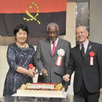 Angolan Ambassador Joao Miguel Vahekeni (center) prepares for a ceremonial cake cutting with Yumiko Akiyama (left), lead researcher of the Japan Institute of Community Social Work, and Manlio Cadelo, San Marino\'s ambassador and dean of the Diplomatic Corps, during a reception to celebrate of the 41st anniversary of the independence of the Republic of Angola at the Palace Hotel Tokyo on Nov. 11. | YOSHIAKI MIURA