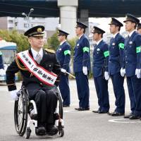 Wheelchair athlete Hiroyuki Yamamoto reviews police officers in the city of Fukuoka on Wednesday as a one-day commander during a public relations event aimed at eliminating drunken driving. The marathoner in the Rio de Janeiro Paralympics lost his 16-year-old son in 2011 after he was hit by a drunken driver. | KYODO
