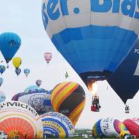 Hot air balloons fly above the city of Saga on Monday, the opening day of the FAI World Hot Air Balloon Championship. The competition runs through Sunday. A total of 105 balloons from 31 countries and regions are participating. | KYODO