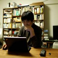 Seijiro Katsura checks market rates for investment opportunities using his laptop at his home in Tokyo on Saturday. | REUTERS