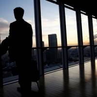 An IT engineer who wishes to remain anonymous poses by the window of a Tokyo office building after being interviewed by Reuters on Dec. 7. | REUTERS