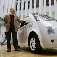 Steve Mahan, who is blind, stands by a Waymo driverless car during a Google event held Dec. 13 in San Francisco. Driverless vehicles may one day help people with visual impairments to travel by themselves. | AP
