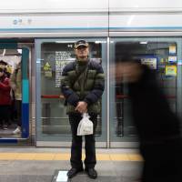 Deliveryman Cho Yong-moon, 75, carries a parcel at a subway station in Seoul on Monday. | BLOOMBERG