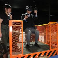 A man tries a virtual reality game called \"Dive Hard\" in which the player scales a skyscraper and fights robots at a media preview of new VR arcade in Tokyo\'s Shibuya Ward on Wednesday. | KAZUAKI NAGATA