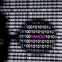 A photo illustration shows a Yahoo logo seen through a magnifying glass in front of a displayed cyber code on Friday. | REUTERS