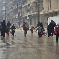 Syrians leave a rebel-held area of Aleppo toward the government-held side on Tuesday during an operation by Syrian government forces to retake the embattled city. U.N. chief Ban Ki-moon expressed alarm over reports of atrocities against civilians Monday, as the battle for Aleppo entered its final phase with Syrian government forces on the verge of retaking rebel-held areas of the city. | AFP-JIJI