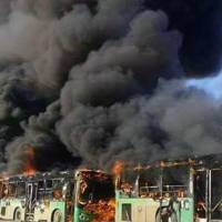 In this photo released by the Syrian official news agency SANA, smoke rises in green government buses, in Idlib province, Syria, Sunday. Activists said, militants have burned at least five buses assigned to evacuate wounded and sick people from two villages in northern Syria. The incident could scuttle a wider deal that encompasses the evacuation of thousands of trapped rebel fighters and civilians from the last opposition foothold in east Aleppo. | SANA VIA AP