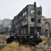 A member of the Syrian pro-government forces stands next to a tank in the old city of Aleppo on Tuesday after they recaptured the area. After weeks of heavy fighting, regime forces were poised to take full control of Aleppo, dealing the biggest blow to Syria\'s rebellion in more than five years of civil war. | AFP-JIJI