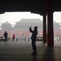 A man wearing a mask for protection against smog visits the Forbidden City in Beijing on Wednesday. | AFP-JIJI