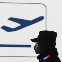 An airport security guard masked against heavy smog stands on duty at Beijing\'s international airport Wednesday. | AP