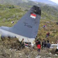 Rescuers collect personal belongings of the victims of an Indonesian Air Force plane that crashed in the mountainous area in Wamena, Papua province, Indonesia, Sunday. The Hercules C-130 transport plane crashed in bad weather in the easternmost province, killing all on board. | AP