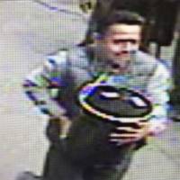 An unidentified man is shown in this image from surveillance video carrying an 86-pound pail of gold flakes valued at &#36;1.6 million off an armored truck two months ago in Manhattan. | COURTESY OF NYPD / HANDOUT VIA REUTERS