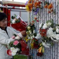 A woman places flowers at a makeshift memorial on Saturday near the scene of a deadly fire in Oakland, California. | REUTERS