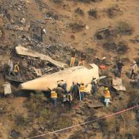Rescue workers survey the site of a plane crash near Abbotabad, Pakistan, on Thursday. | REUTERS