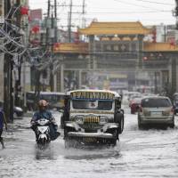 A jeepney navigates a flooded street in Quezon City, north of Manila, following heavy rain after Typhoon Nock-Ten hit the Philippines on Monday. | AP