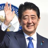 Prime Minister Shinzo Abe waves to well-wishers prior to boarding a government plane at Tokyo\'s Haneda airport on Nov. 17. | AFP-JIJI
