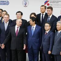 Russian President Vladimir Putin and Prime Minister Shinzo Abe pose with delegates at a meeting of the Russian-Japanese Business Council on Friday. | KYODO