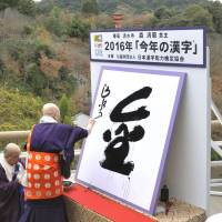 The kanji for kin, meaning gold or money, is written at Kiyomizu Temple in Kyoto on Monday by chief priest Seihan Mori after it was selected the kanji of the year. | KYODO