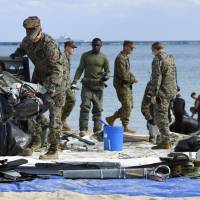 U.S. military personnel Saturday collect wreckage from the debris field left by a U.S. Marine Corps MV-22 Osprey aircraft that crash-landed Tuesday off the coast of Okinawa Prefecture. | KYODO