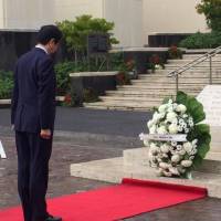 Prime Minister Shinzo Abe lays a wreath at the National Memorial Cemetery of the Pacific in Honolulu on Monday morning. | ERIC JOHNSTON