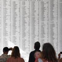 Visitors to the USS Arizona Memorial in Hawaii on Dec. 11 observe a list of names of those who died in the 1941 Japanese attack on Pearl Harbor. | KYODO