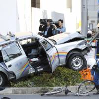 A taxi that crashed through an intersection and onto a sidewalk in Tokyo\'s Kita-Aoyama district on Tuesday was seriously damaged. The accident injured six people, including the driver. | KYODO