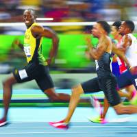 Jamaican sprinter Usain Bolt turns to look at Canada’s Andre De Grasse during the men’s 100-meter semifinals. | REUTERS