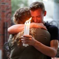 Brett Morian hugs a woman at a candlelight vigil in Orlando, Florida, following a mass shooting at the Pulse gay nightclub. | AP