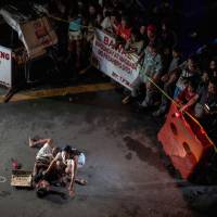 Jennilyn Olayres grieves beside the body of her partner, Michael Siaron, who was shot by an unidentified gunman in Manila and left with a cardboard sign reading, \"I\'m a pusher.\" | AFP-JIJI
