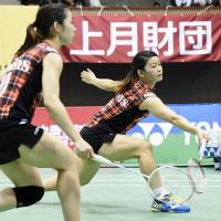 Ayaka Takahashi reaches for a shot as teammate Misaki Matsutomo watches on during a game at the national badminton championships on Sunday. | KYODO