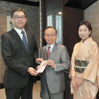 Tea ceremony school Chanoyu International Executive Director Takeya Yamasaki (second from left) presents The Japan Times President Takeharu Tsutsumi a &#165;342,000 contribution for The Japan Times Readers\' Fund at The Japan Times on Dec. 9. The money will be shared among overseas charities, including NPOs that help poor Cambodians and Filipinos secure better access to education. | YOSHIAKI MIURA