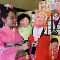 Staffer Megumi Kondo of doll-maker Kyugetsu shows off hagoita ornamental paddles bearing faces of some of the year\'s newsmakers, including U.S. President-elect Donald Trump and Tokyo Gov. Yuriko Koike. They will be on display at the firm\'s headquarters in Tokyo until Sunday. | SATOKO KAWASAKI