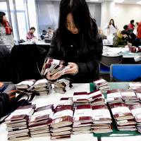 A Chinese travel agency worker prepares passports for tourist visas at the Japanese Embassy in Beijing on Jan. 20 ahead of Lunar New Year holidays. Japanese retailers focus on selling experiences in Lunar New Year Campaigns
