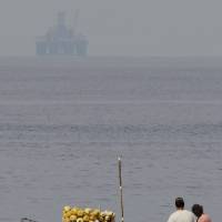 An oil rig floats in the distance as fishermen work in Havana Bay, Cuba, in 2012. Cuba and the United States signed an accord on Monday on preventing and cleaning up oil spills in the Gulf of Mexico and the Florida Straits. | AP