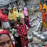 Rohingya women and children wait to collect water at the Leda camp, an unregistered camp for Rohingya in Teknaf, near Cox\'s Bazar in southern Bangladesh, on Dec. 3. | AP