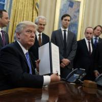 President Donald Trump shows off a signed executive order to reinstitute a policy barring any recipient of U.S. assistance from performing or promoting abortions abroad with money they receive from non-U.S. sources, on Monday in the Oval Office of the White House in Washington. On heels of women's march, Trump bans federal funds for foreign NGOs that back abortions