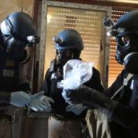A U.N. chemical weapons expert holds a bag containing samples from one of the sites of an alleged chemical weapons attack in the Ain Tarma neighborhood of Damascus in August 2013. | REUTERS