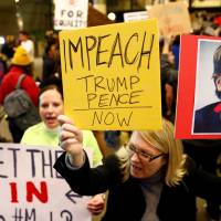 Women hold signs against Steve Bannon and encouraging the impeachment of Trump and Pence during a protest of Donald Trump\'s travel ban from seven Muslim majority countries, at the International terminal at Los Angeles International Airport (LAX) Saturday. | REUTERS
