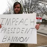 A protester holds a sign calling for the removal of Chief White House strategist Steve Bannon outside the White House in Washington Monday. | REUTERS