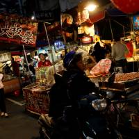 Visitors stroll through a food stall at Raohe street Night Market in Taipei last Wednesday. | REUTERS