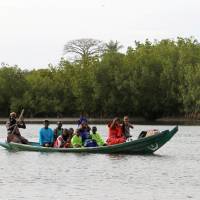 Gambian refugees in a wooden canoe approach a beach in the Senegalese village of Niafarang on Tuesday. | REUTERS
