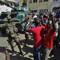 Gambians celebrate outside of the Statehouse in Banjul on Monday. The Gambia awaited the arrival of President Adama Barrow as his team said former strongman Yahya Jammeh plundered the nation’s coffers before going into exile. Gambia, under yet-to-arrive new leader, frees political prisoners rounded up, tortured by predecessor