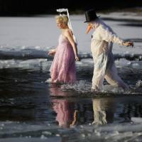 A costumed couple walks into frozen Lake Orankesee on Saturday. | AP