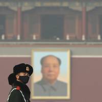Chinese paramilitary policemen wearing masks to protect against pollution watch visitors near a portrait of Mao Zedong on Tiananmen Square in Beijing on Jan. 4. | AP