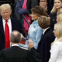 Donald Trump takes the presidential oath of office at the Capitol on Friday with his wife, Melania, and children at his side. | REUTERS