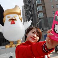 A woman takes a selfie in front of a sculpture of a rooster that local media say bears resemblance to U.S. President-elect Donald Trump, outside a shopping mall in Taiyuan, China, on Dec. 30. | REUTERS