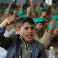 A boy shouts slogans next to injured pro-Houthi fighters, during a rally held to honor those injured or maimed while fighting in Houthi ranks in Sanaa Sunday. | REUTERS