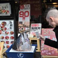 A tourist photographs the head of a freshly caught tuna at a sushi restaurant in Tsukiji, Tokyo. | YOSHIAKI MIURA